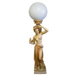 A resin figural floor standing lamp of a semi-naked slave girl: holding a cornucopia shell on her