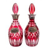 A pair of ruby and clear overlay glass decanters and stoppers: with plated mounts and labels,