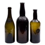 A group of three green glass sealed wine bottles: including a George III cylindrical bottle with