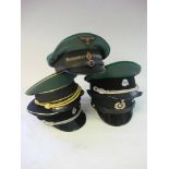 A collection of five reproduction German military peaked caps and a small group of cloth badges.