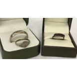 3 silver rings. A plain silver band, a oval signet ring with floral decoration and a half eternity