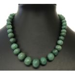 A graduating jade bead necklace with gold tone clasp and extension chain.