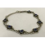 A decorative 7 panel bracelet set with small round Lapis Lazuli stones with extension chain.