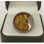 A contemporary design circular silver ring set with amber.