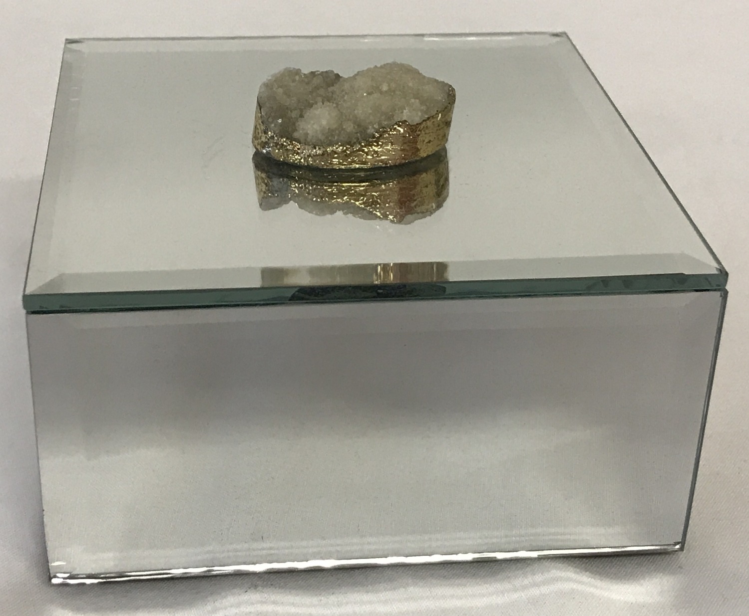 A modern mirrored jewellery box with druzy stone set as lid handle.