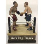 A painted cast metal novelty money box in the shape of a boxing ring.