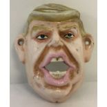 A painted cast metal wall hanging bottle opener in the shape of Donald Trump.