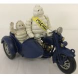 A painted cast iron figurine of a Michelin man riding a motorcycle and sidecar.