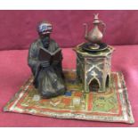 After Bergman, a cold painted figural desk inkwell depicting an Arabian man kneeling on a carpet.