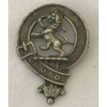 A white metal Scottish rampant lion clan badge.