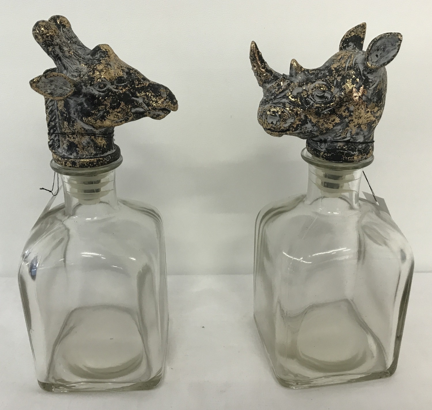 A pair of square shaped bottle decanters with animal head stoppers.