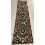 A vintage floor runner with green background and red, blue, cream and gold tones.