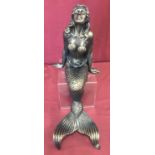 A large cast metal figurine of a mermaid in a seated position.