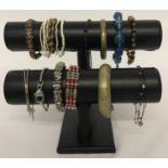 A black 2 tier jewellery display stand with a quantity of costume jewellery bracelets.