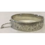 A vintage half floral engraved bangle complete with safety chain.