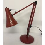 A vintage red metal angle poise lamp.
