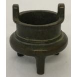 A small Chinese bronze 3 foot censer with loop handles and shaped bowl.