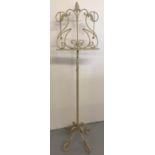 A modern ornate cream metal music stand with decorative feet & rest and chained page weights.