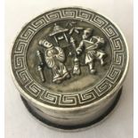 A Chinese white metal rouge pot with figural detail to lid and Greek key design to rim.