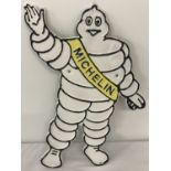A painted metal wall hanging plaque in the shape of a Michelin man.