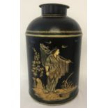 A black painted Tole ware, lidded tea jar with fisherman detail to front.