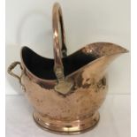 A vintage copper coal scuttle with hinged handle.