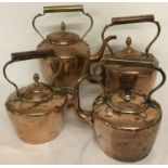 Four vintage copper kettles of varying sizes and designs.