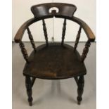 A vintage dark wood captains chair with turned details to spindles.