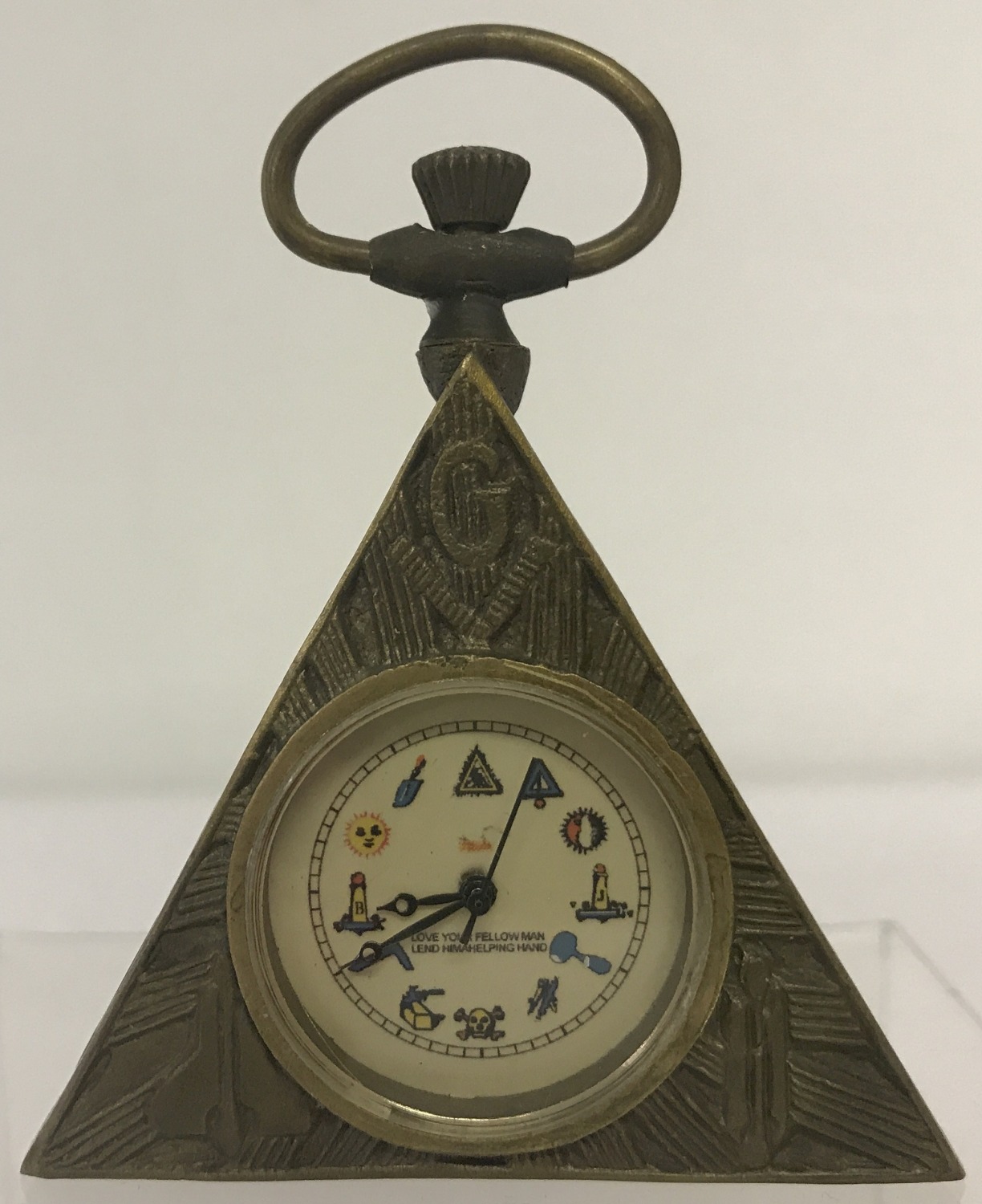 A small brass cased, triangular shaped pocket watch with Masonic style decoration.