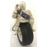 A painted cast iron figure of a Michelin man sitting atop a tyre.