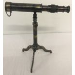 A small brass telescope mounted on an extending tripod base with folding feet.