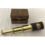 A small 3 draw brass telescope in a wooden box with brass anchor motif.