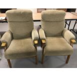 A pair of beige velour armchairs with wooden frames.