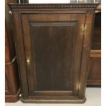 An antique dark oak corner cupboard. 3 interior shelves with curved fronts.