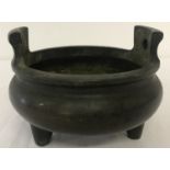 A large Chinese bronze, 2 handled censer raised on tripod feet.