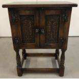 A small vintage dark wood 2 door cupboard with carved detail to front.