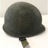 A US army M1 steel helmet with trench art detail, complete with liner.