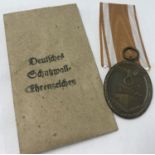 A German WWII style West Wall medal and packet.