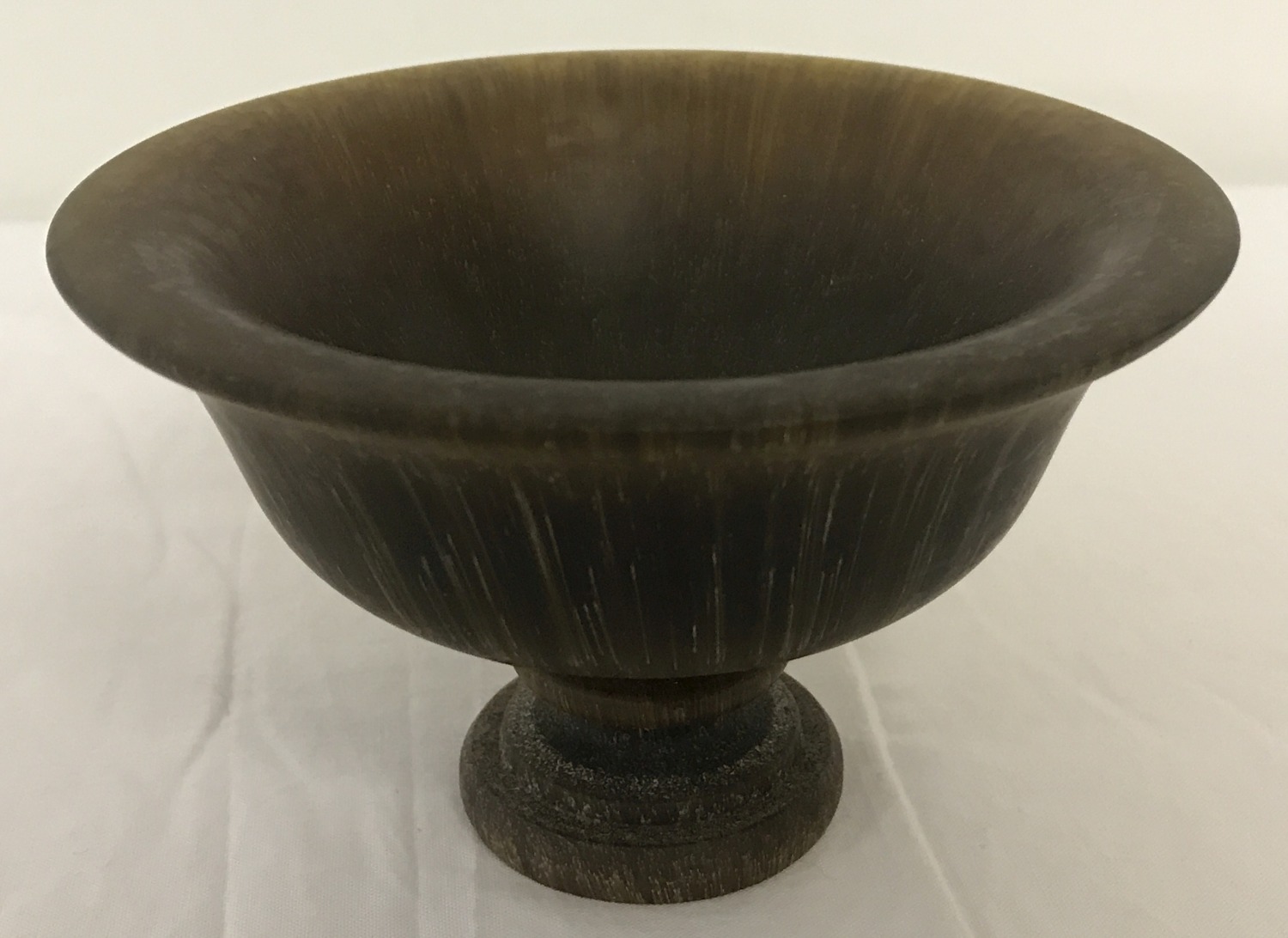 A circular shaped libation cup raised on a central pedestal base.