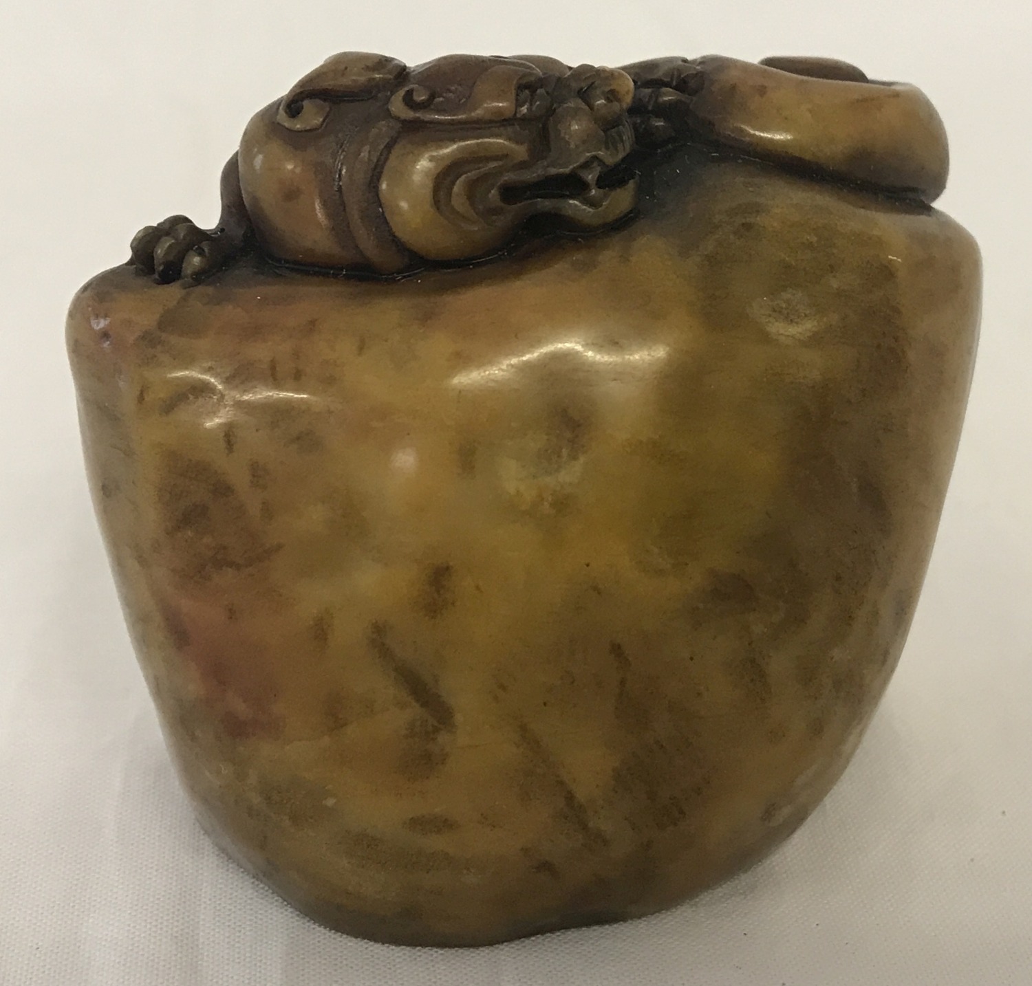 A decorative Oriental soapstone seal with carved dragon detail.