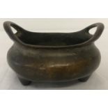 A small Chinese bronze 2 handled censer raised on tripod feet.