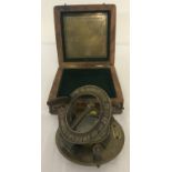 A brass sundial and compass in wooden box.