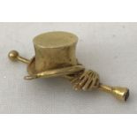 A 9ct gold top hat, cane and gloves charm. Cane set with a garnet to end.