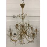 A vintage brass and glass 2 tier chandelier with crystal string and drop decoration.