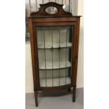 A small Edwardian bow fronted glass fronted display cabinet with inlaid detail and mirrored back.