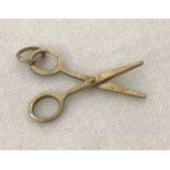 A gold pendant/charm in the shape of a pair of scissors. With moving parts.