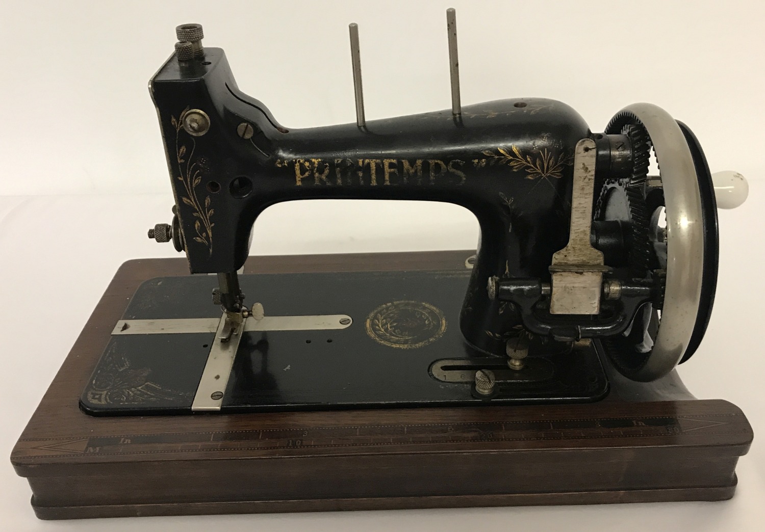 A vintage Printemps hand sewing machine with gilt detail, folding enamel handle & inlaid wooden base
