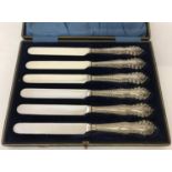 An Edwardian set of silver butter knives in original case with classic decoration to handles.
