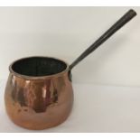 An antique copper saucepan with riveted handle.