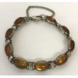 A modern design bracelet set with 9 amber cabochon stones. Complete with safety chain.